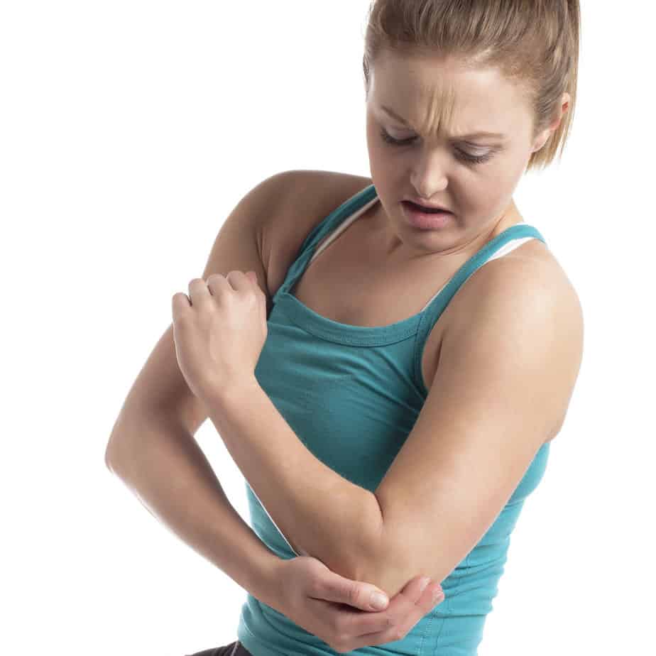 Blonde, white, thin women in a teal tank top holding making a face as she holds her elbow.