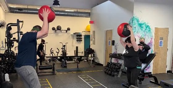 Reimagym coach helping member with functional fitness training during first step session