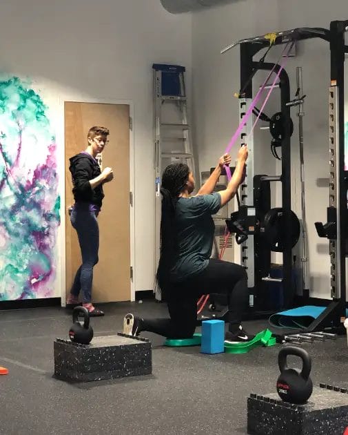 Personal trainer coaching client during workout at Reimagym